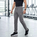 City Center Select men's grey athletic track pants with tapered fit, zippered pockets, and drawstring in a gym setting
