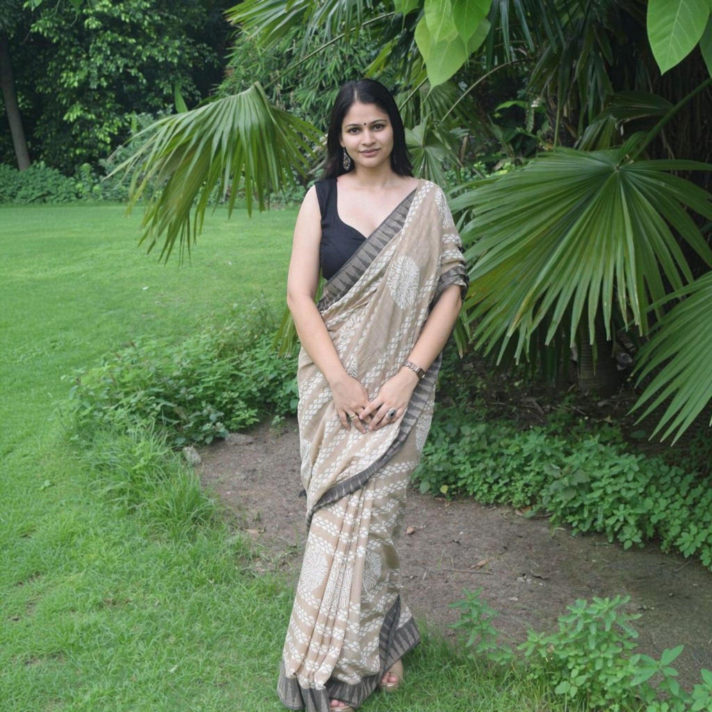 City Center premium cotton saree in beige with white floral motifs and dark border, worn by a woman in a garden.