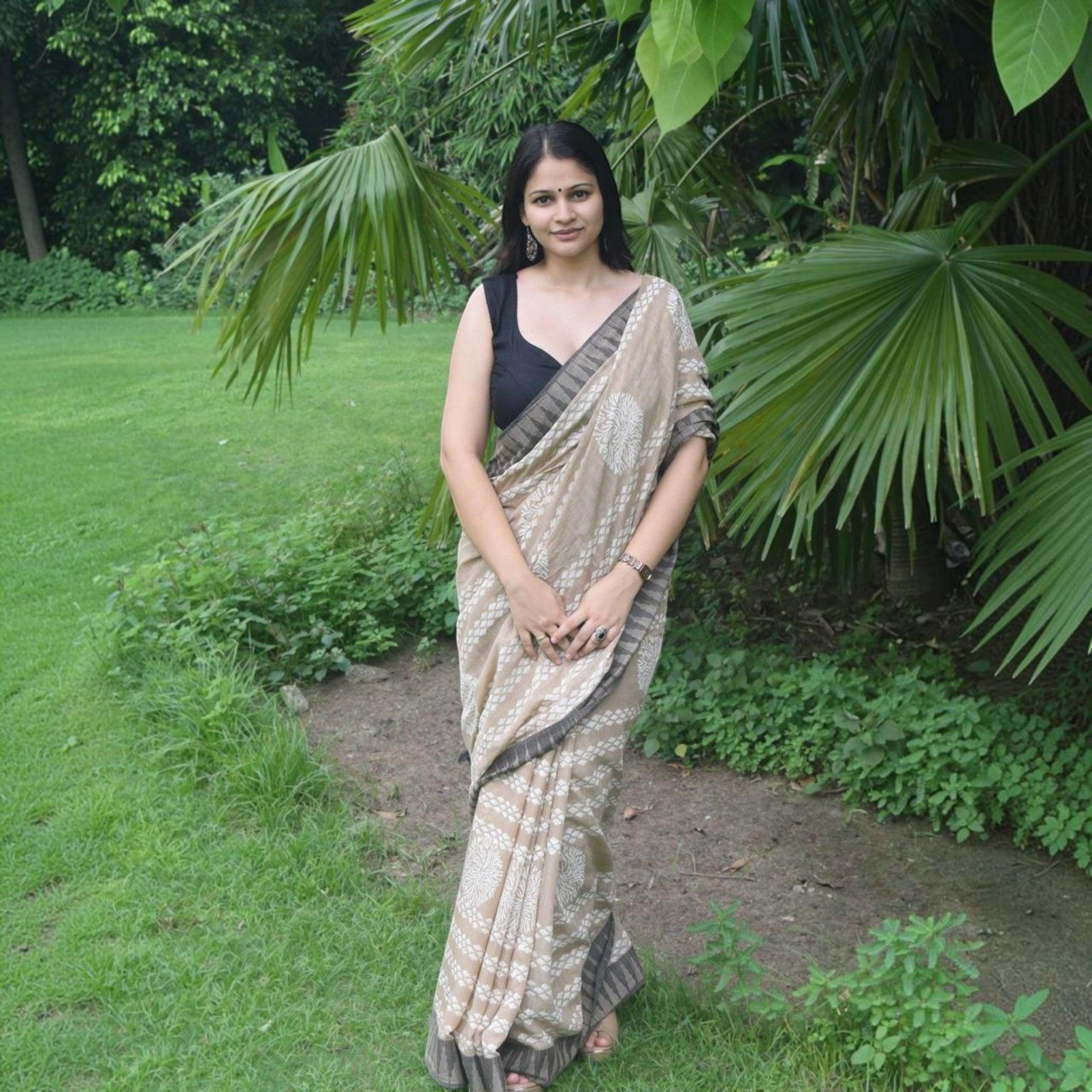City Center premium cotton saree in beige with white floral motifs and dark border, worn by a woman in a garden.