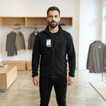 Man wearing a black City Center HICCUPS antipiling fleece jacket with a full zip and chest pocket in a retail store