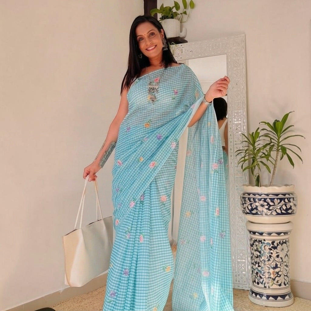 City Center light blue checkered cotton saree with floral embroidery worn by a woman holding a white tote bag