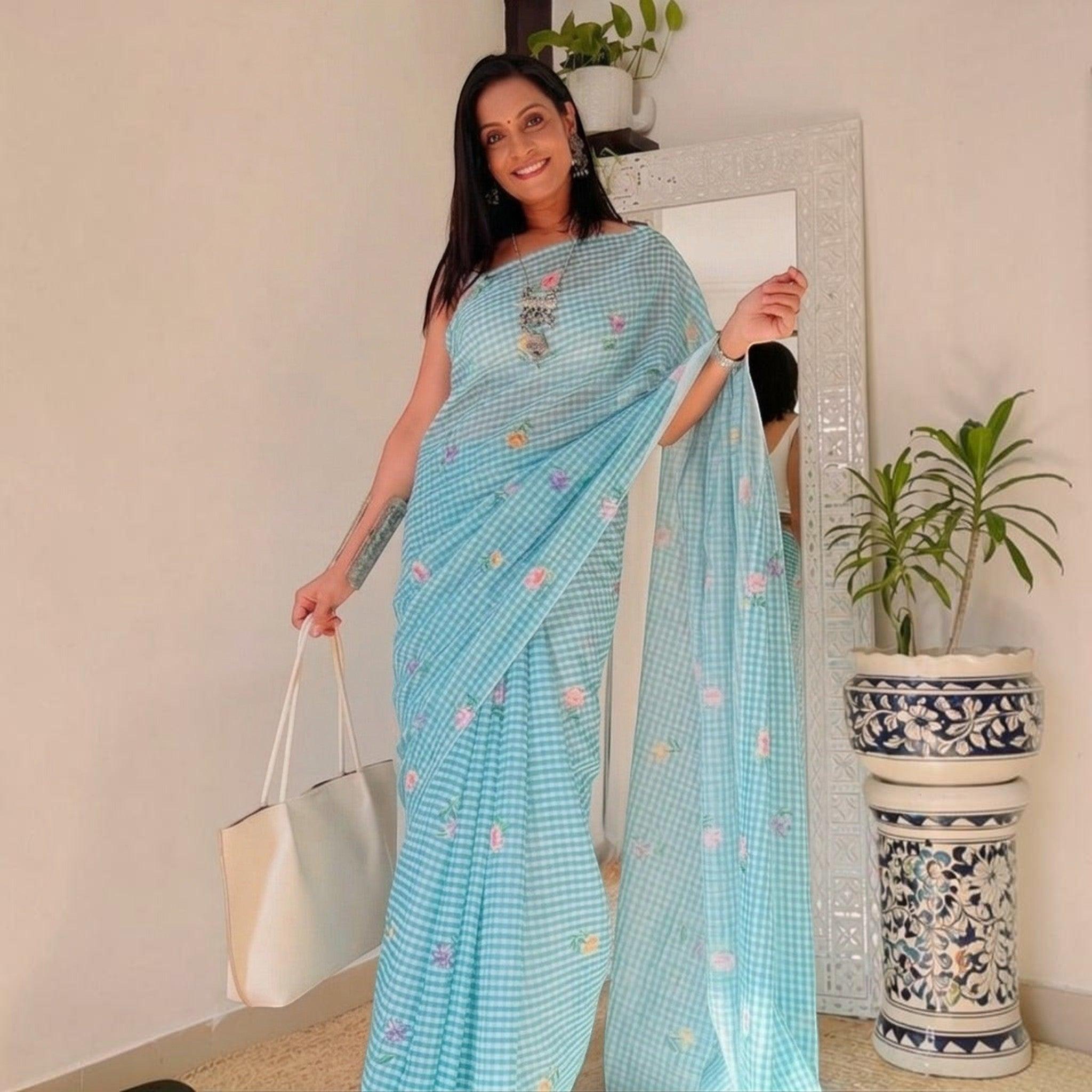 City Center light blue checkered cotton saree with floral embroidery worn by a woman holding a white tote bag