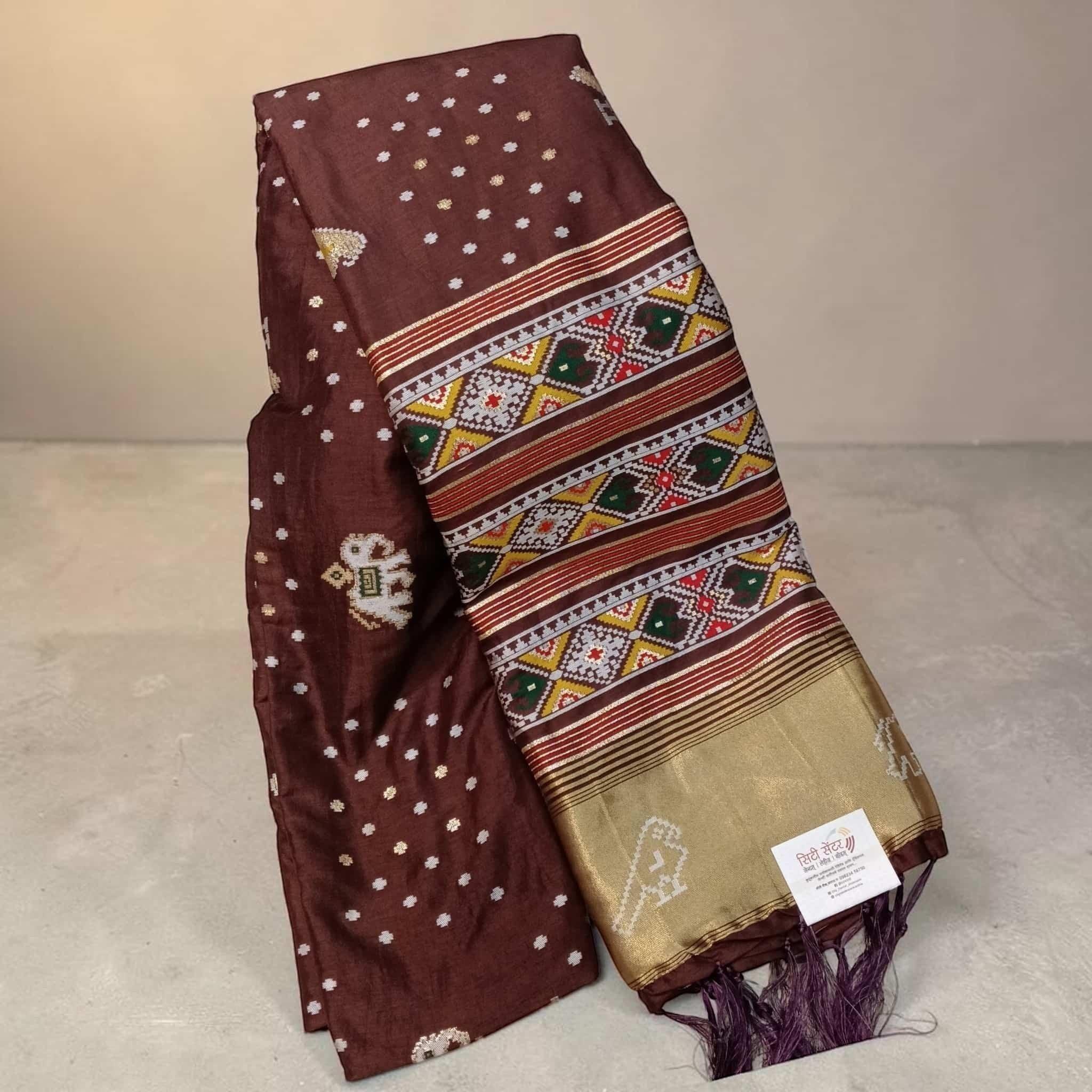 City Center brown silk cotton saree featuring traditional Patola-inspired geometric ikat patterns and gold zari border.