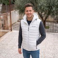 City Center Columbia white hooded puffer vest worn by a man over a grey long-sleeve shirt and blue jeans