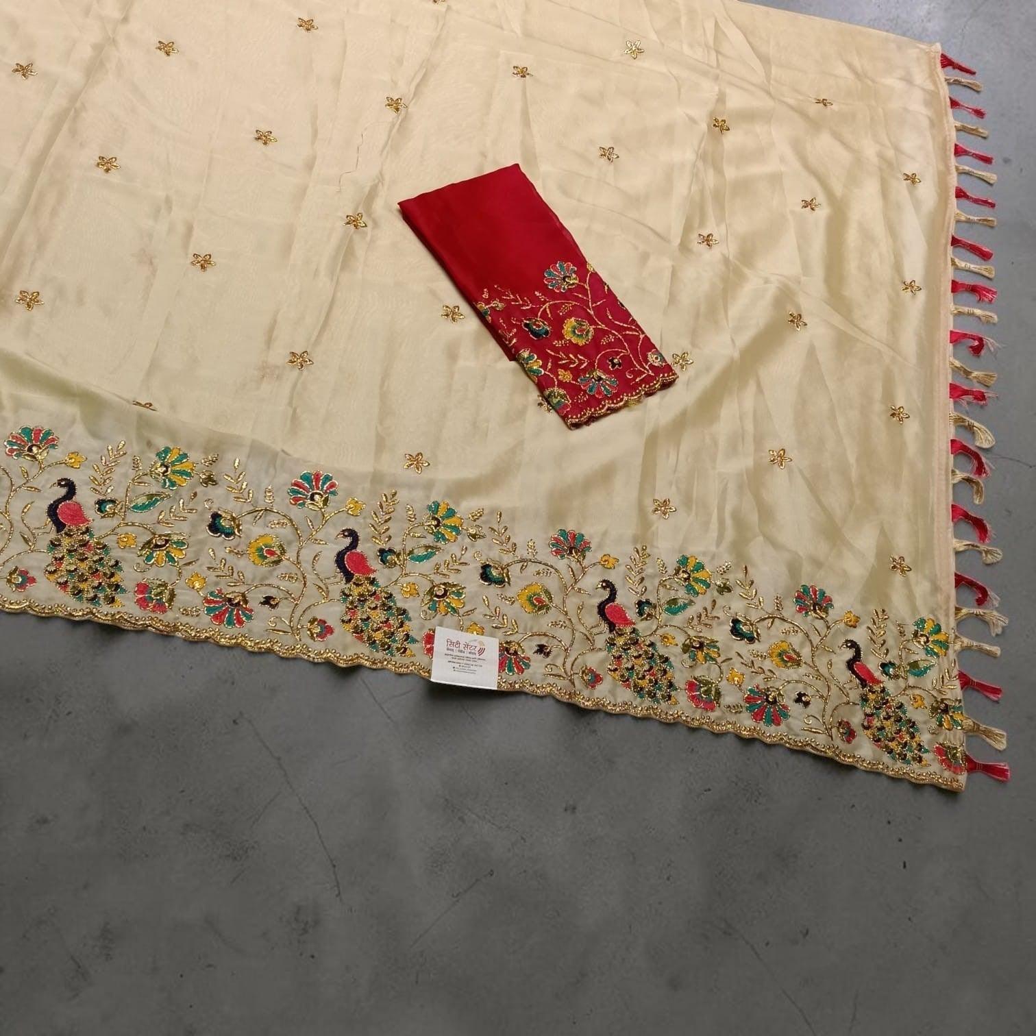 City Center cream saree with peacock embroidery, floral motifs, and a matching red unstitched blouse piece.