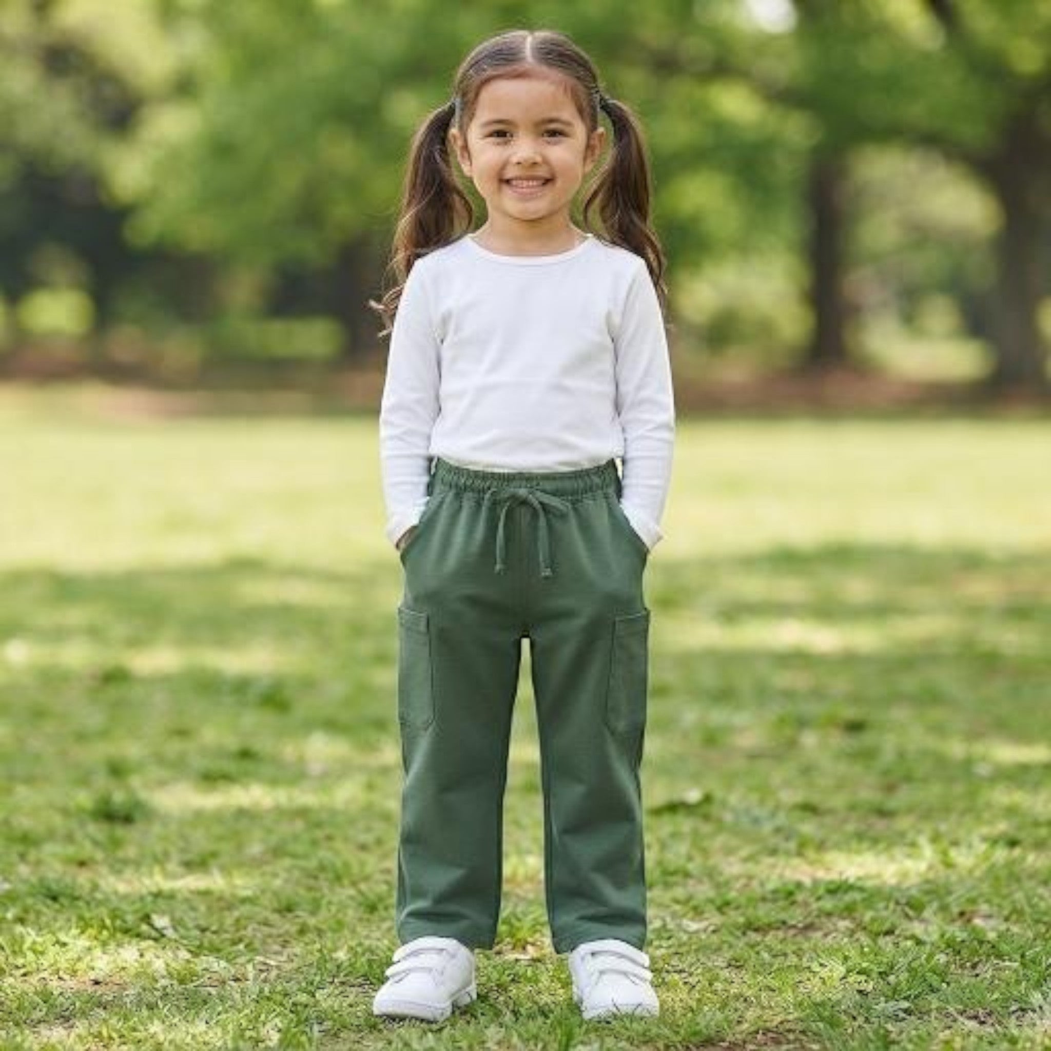 City Center green ethnic pants for girls with an elasticated waistband, worn by a smiling child in a park.