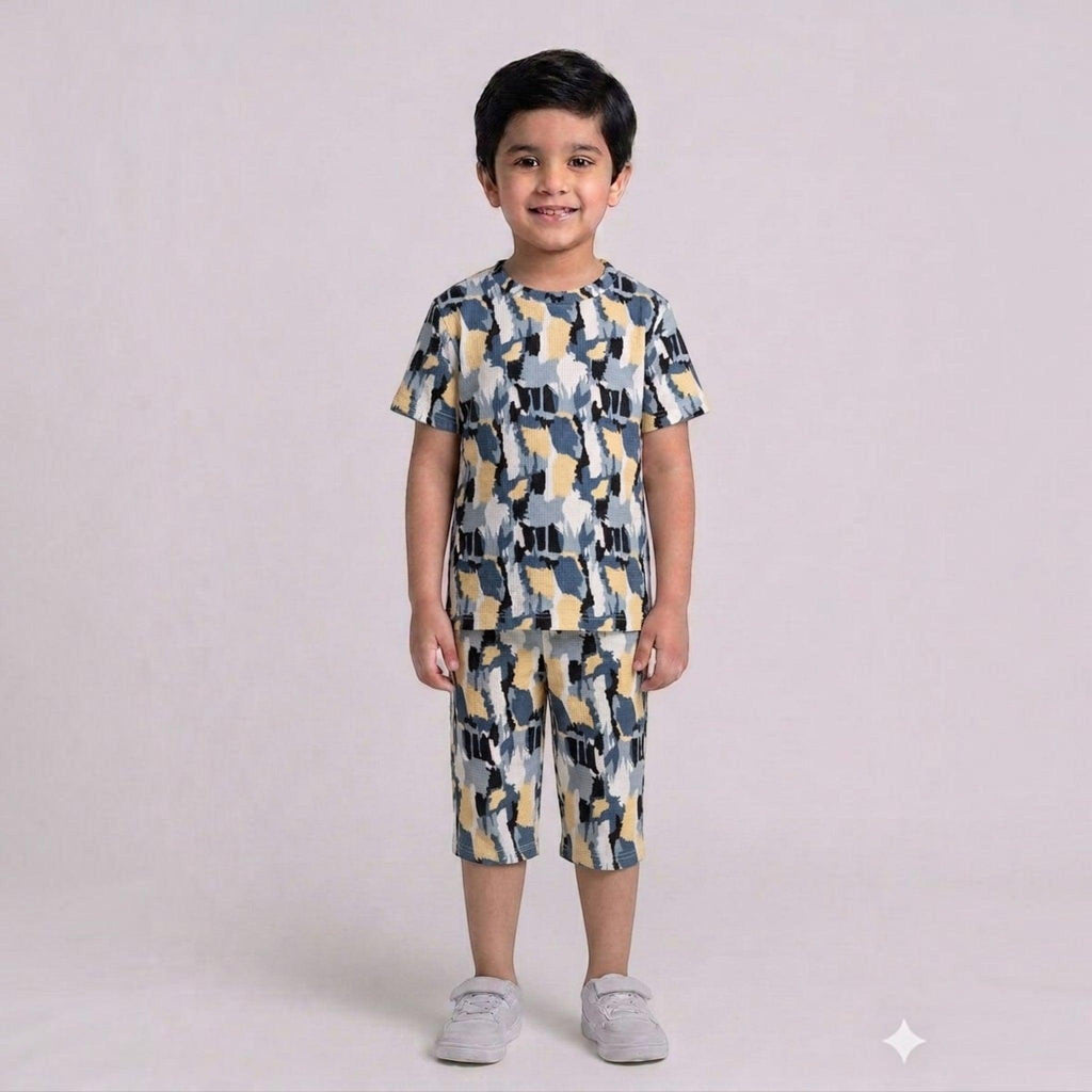 City Center kids cotton co-ord set with a blue, yellow, and grey abstract print worn by a smiling young boy.