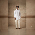 City Center men's white short kurta with mandarin collar and long sleeves, styled with cream trousers and sandals.