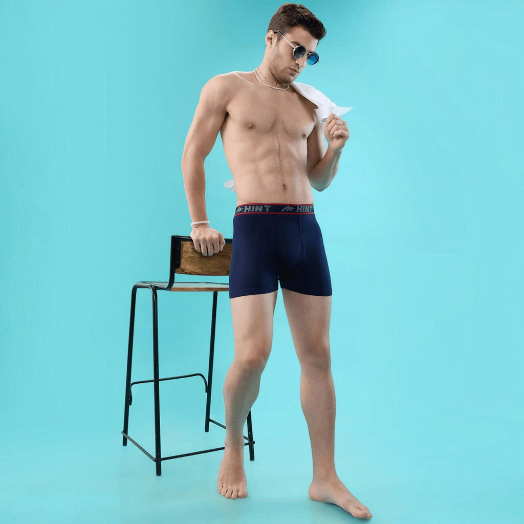 City Center men's navy blue cotton long trunks with an elasticated waistband, worn by a model against a blue background.