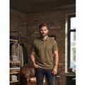 City Center M-Line men's olive green polo shirt with a chest pocket, worn by a man in a rustic clothing store.