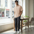City Center men's pastel peach polo shirt with a chest pocket, worn by a model in a bright, modern indoor setting.