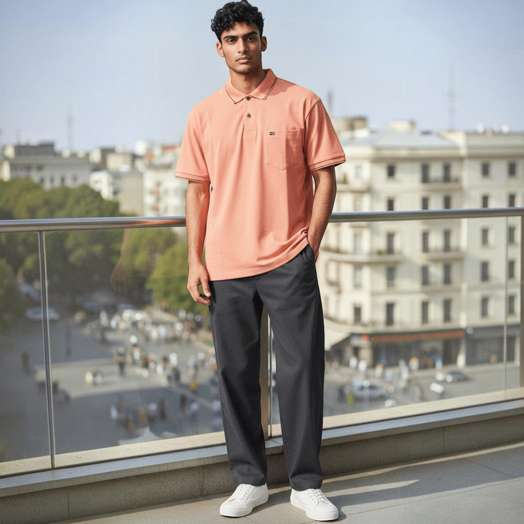 City Center men's peach polo shirt with chest pocket, styled with dark trousers and white sneakers on a balcony.