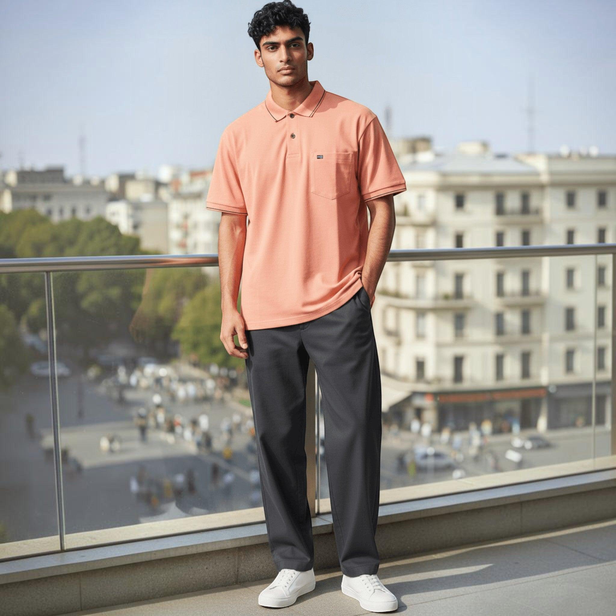City Center men's peach polo shirt with chest pocket, styled with dark trousers and white sneakers on a balcony.