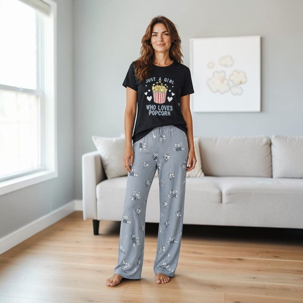 City Center woman wearing a black t-shirt with popcorn graphic and grey patterned pajama pants in a living room