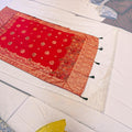City Center red Dola silk saree featuring intricate gold zari floral borders and traditional woven motifs.