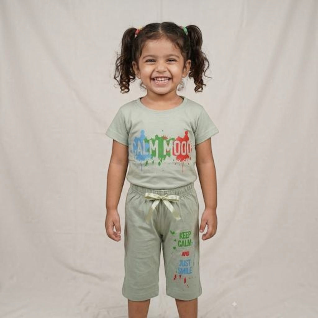 A young girl smiling while wearing a sage green City Center co-ord set with colourful graphic text prints.