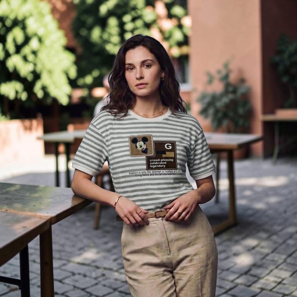 City Center premium cotton t-shirt with grey and white stripes, Mickey Mouse graphic, and text patch, worn by a woman.