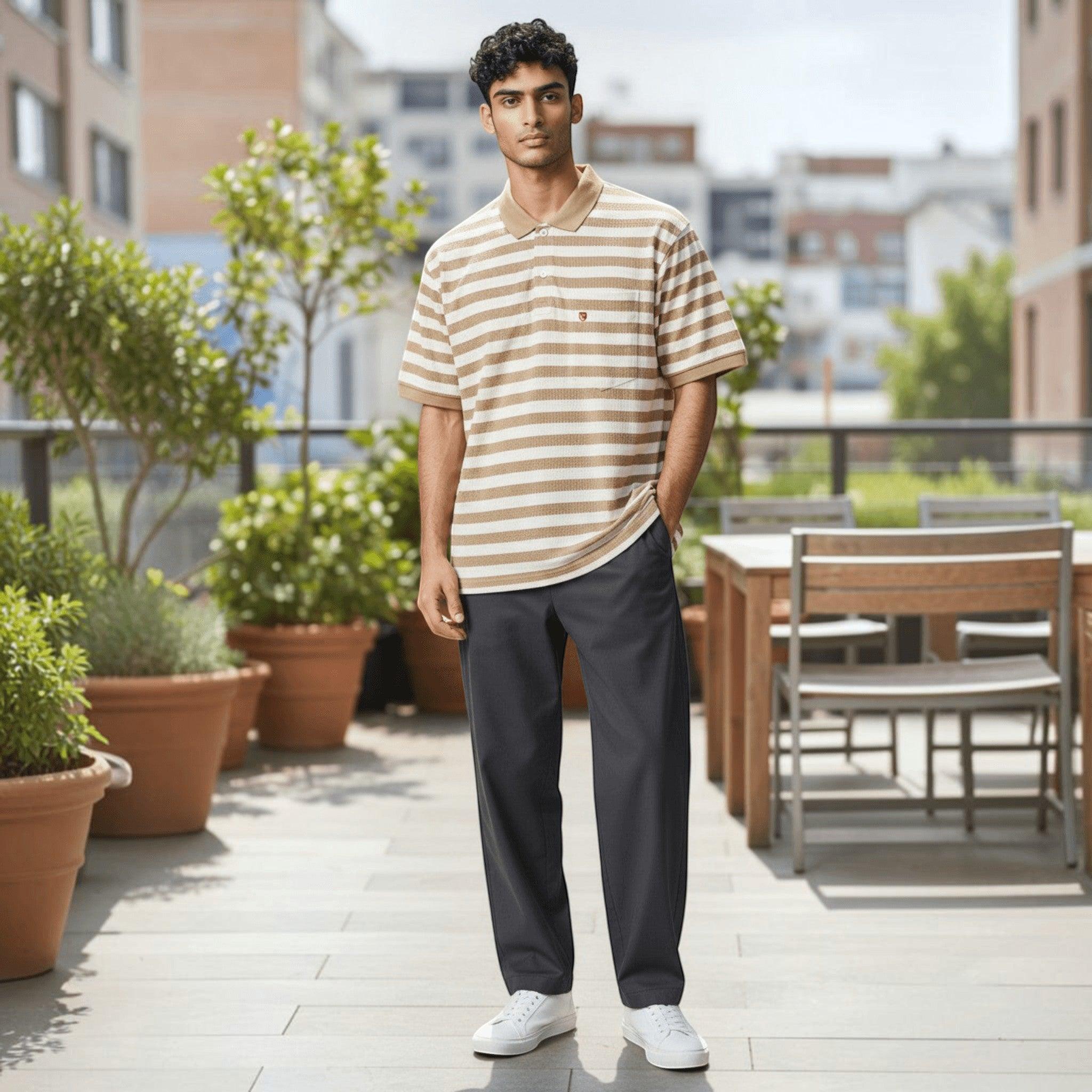 City Center model wearing a beige and white striped polo shirt with dark trousers and white sneakers on a terrace.