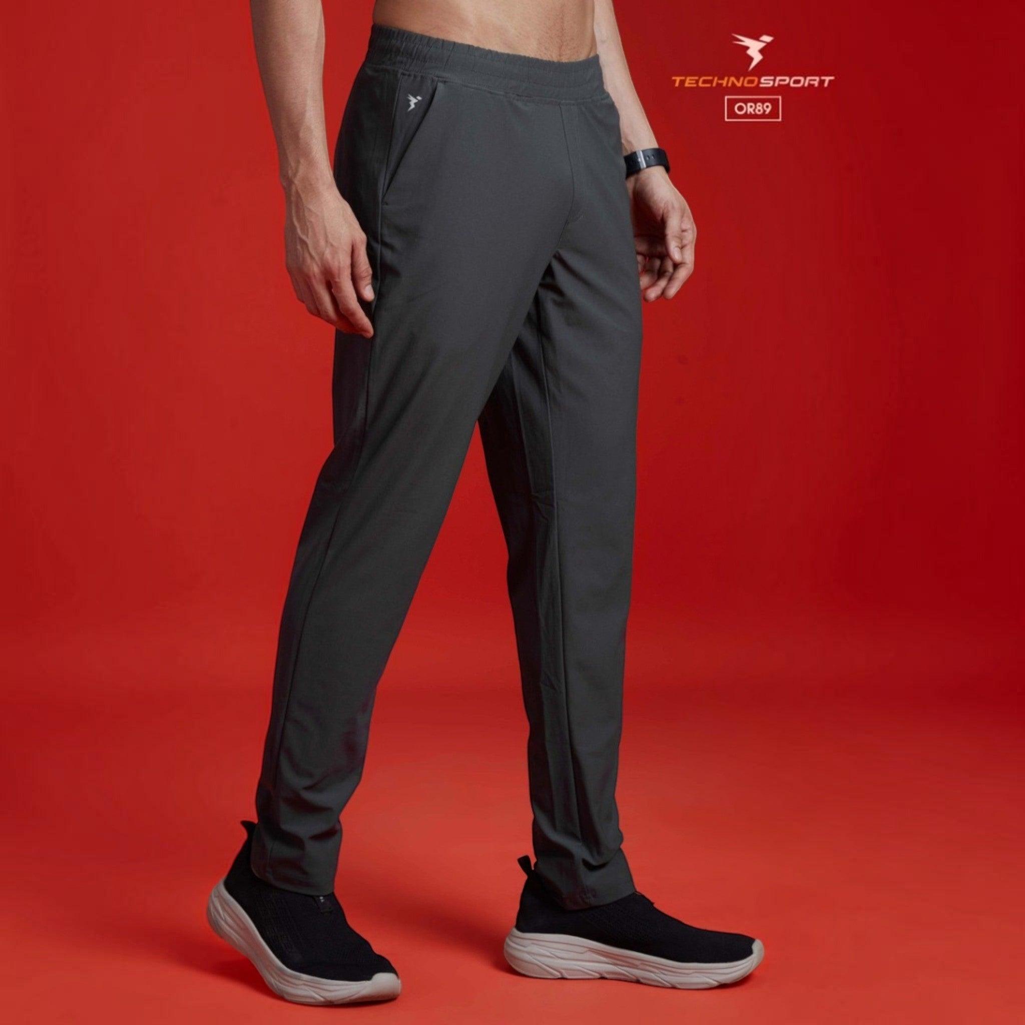 City Center Technosport DuraCool+ solid charcoal grey 4-way stretch track pants on a model against a red background.