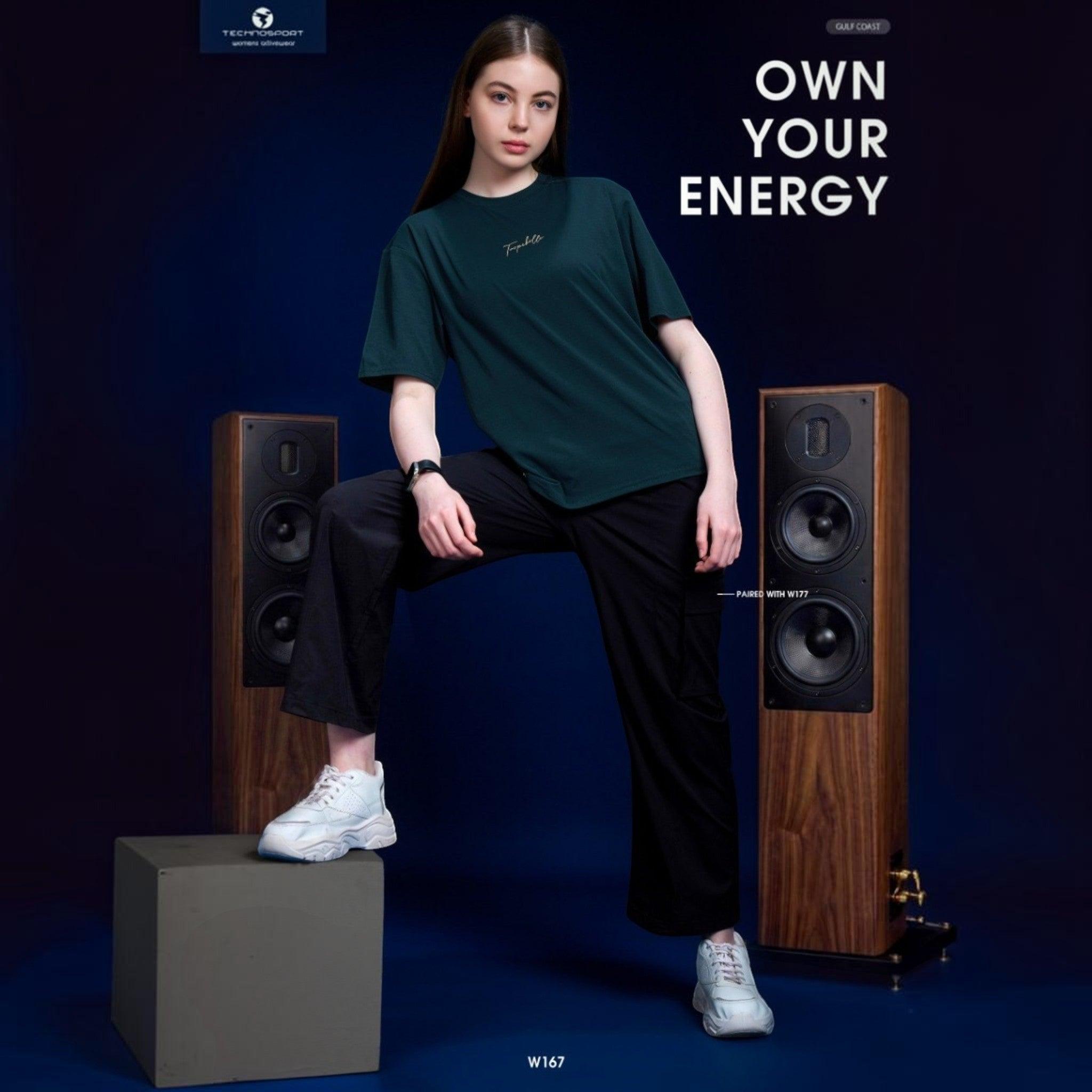 City Center Technosport women's dark green crew neck t-shirt with minimalist branding, worn with black trousers.