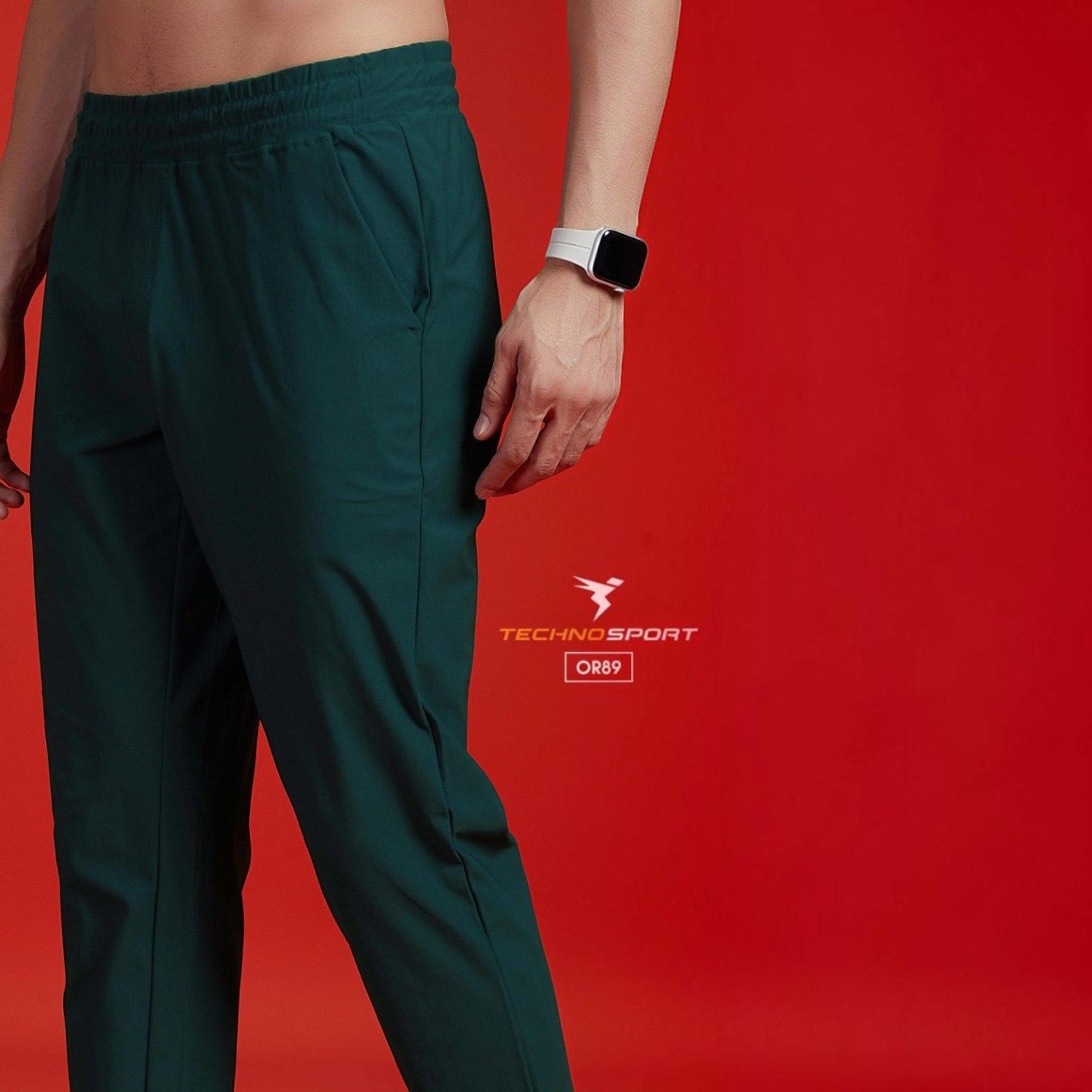 City Center Technosport dark green 4-way stretch track pants with an elastic waistband on a model against a red background