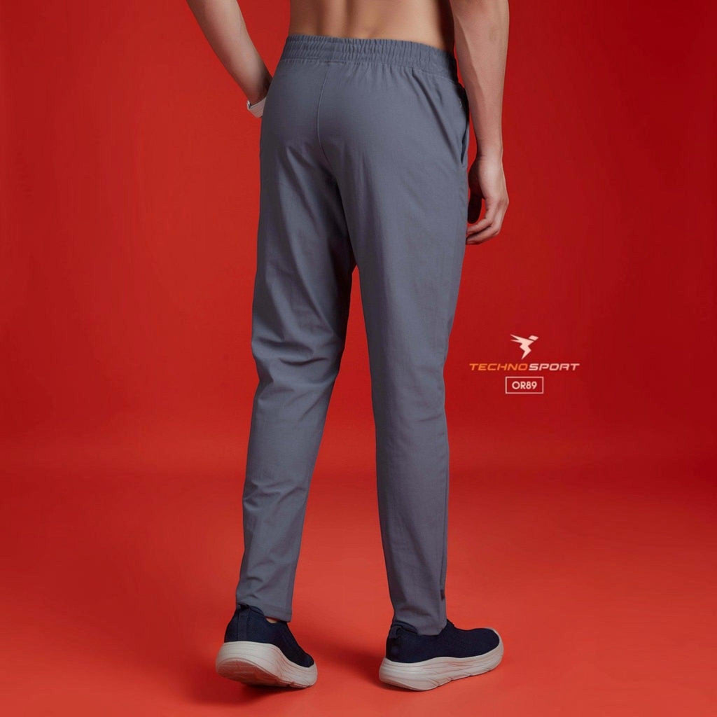 City Center Technosport grey 4-way stretch track pants worn by a man against a red background