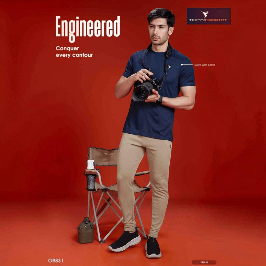 City Center Technosport mens slim fit khaki track pants paired with a navy t-shirt on a model against a red backdrop