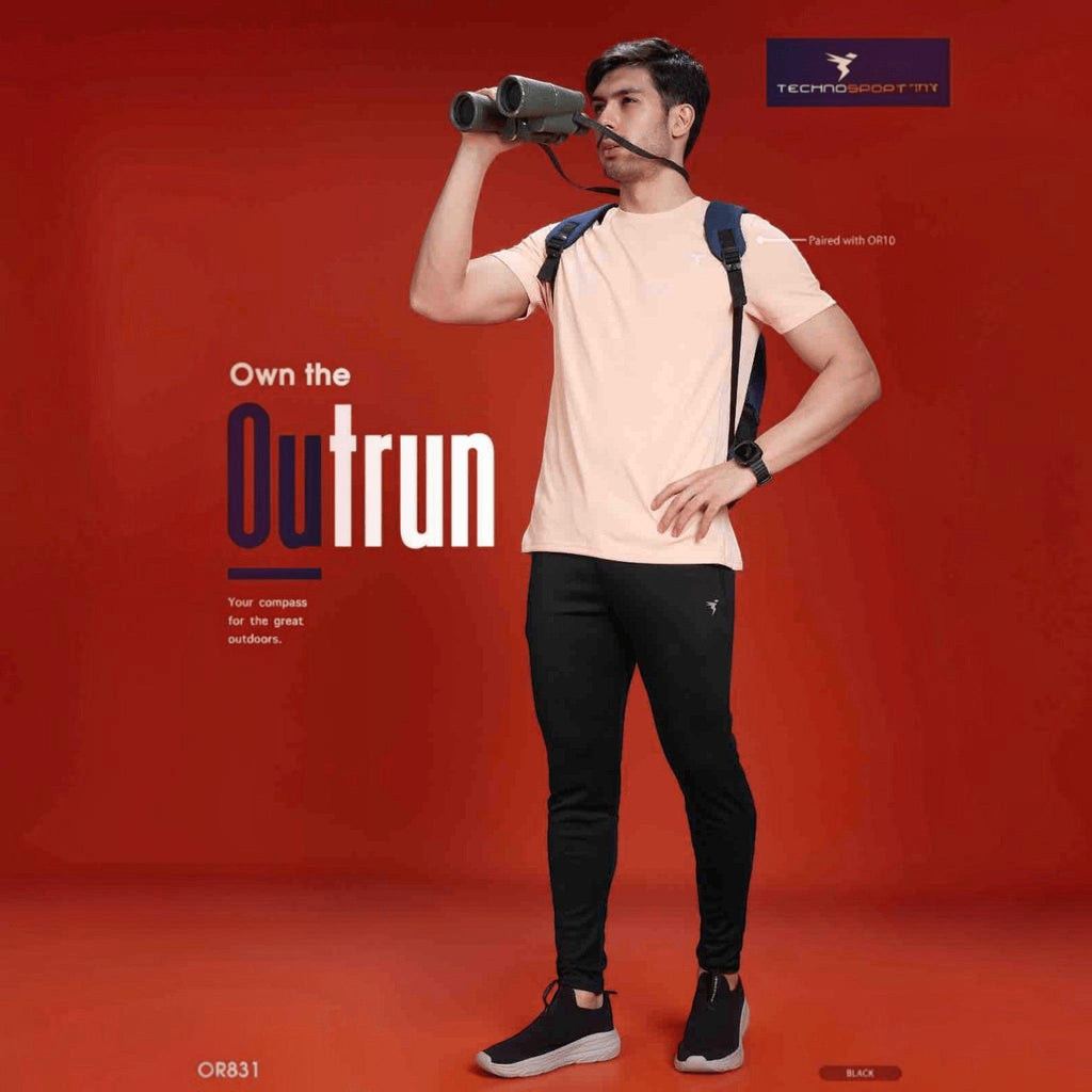 City Center Technosport mens black slim fit performance track pants worn by a model with binoculars on a red background