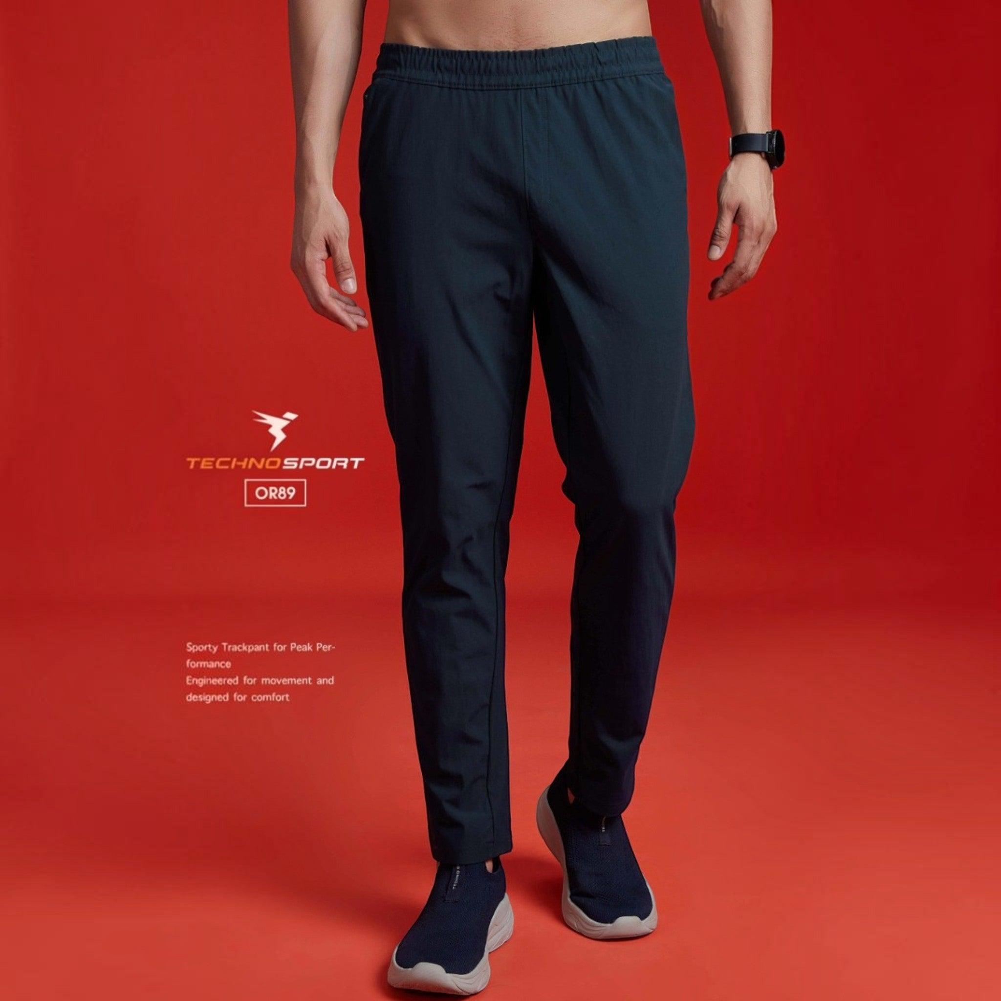 City Center Technosport DuraCool+ solid navy blue 4-way stretch track pants on a model against a red background.