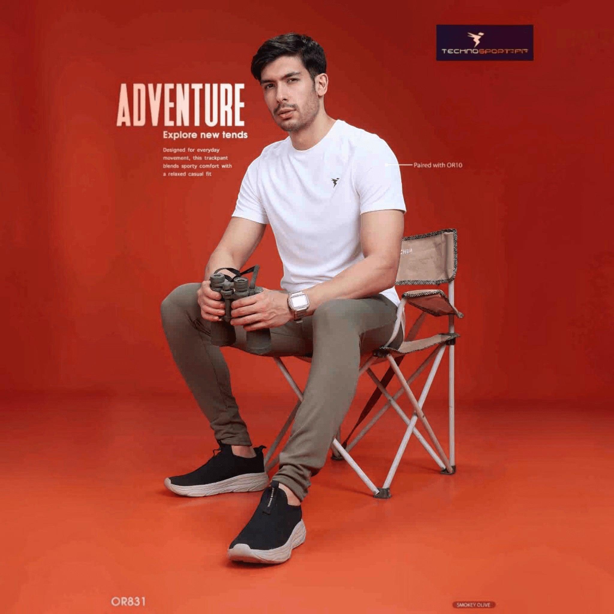 City Center Technosport mens slim fit track pants in smokey olive, worn by a model sitting on a folding chair