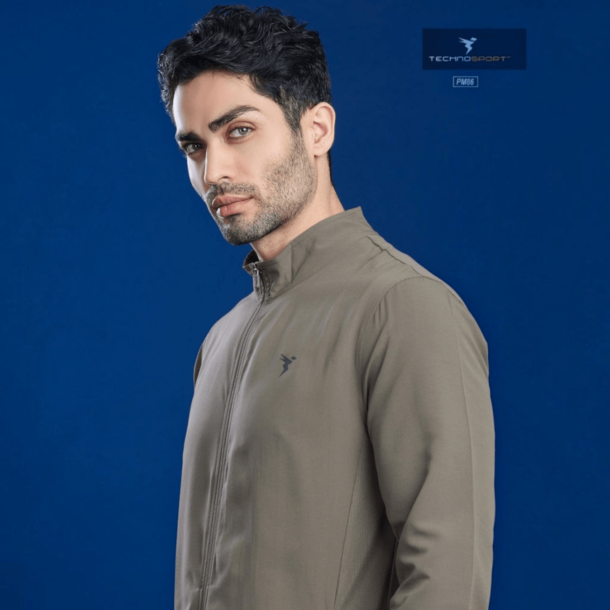 City Center model wearing a taupe Technosport TS Flexi performance jacket with a mock neck and zip-up front.