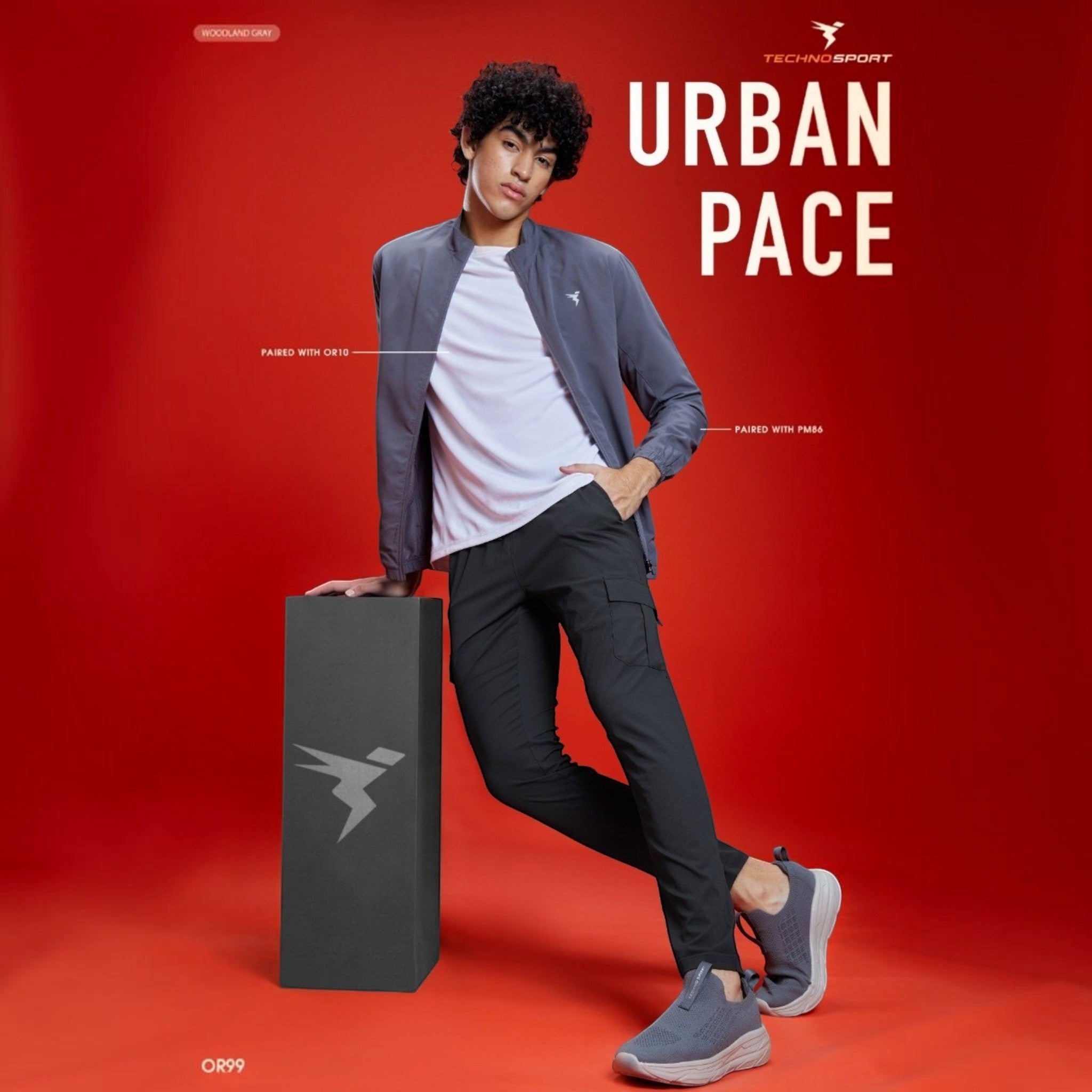 City Center model wearing Technosport TS Flexi solid woven cargo pants in dark grey against a vibrant red background.