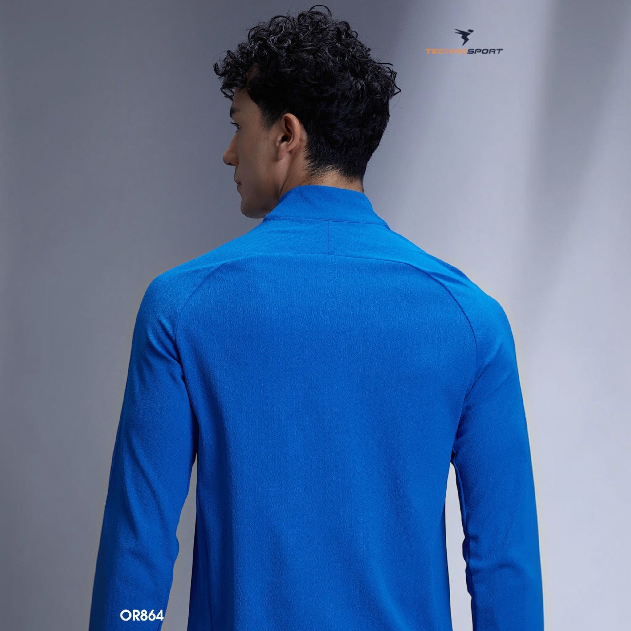 Back view of a male athlete wearing a blue City Center TECHNOSPORTS CloudFlex high neck long sleeve performance tee