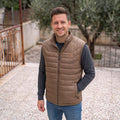 City Center man wearing a brown insulated The North Face vest over a grey sweater outdoors