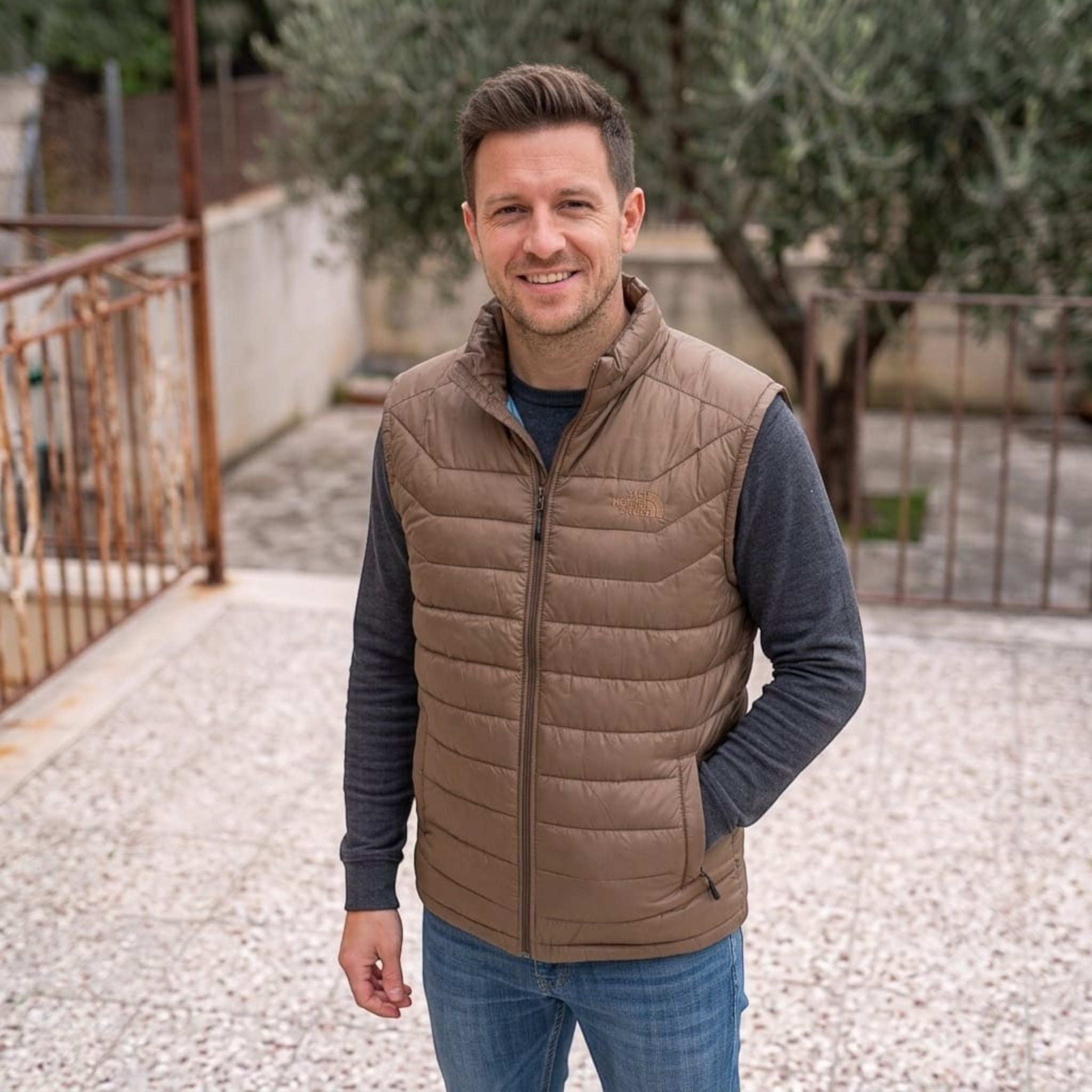 City Center man wearing a brown insulated The North Face vest over a grey sweater outdoors