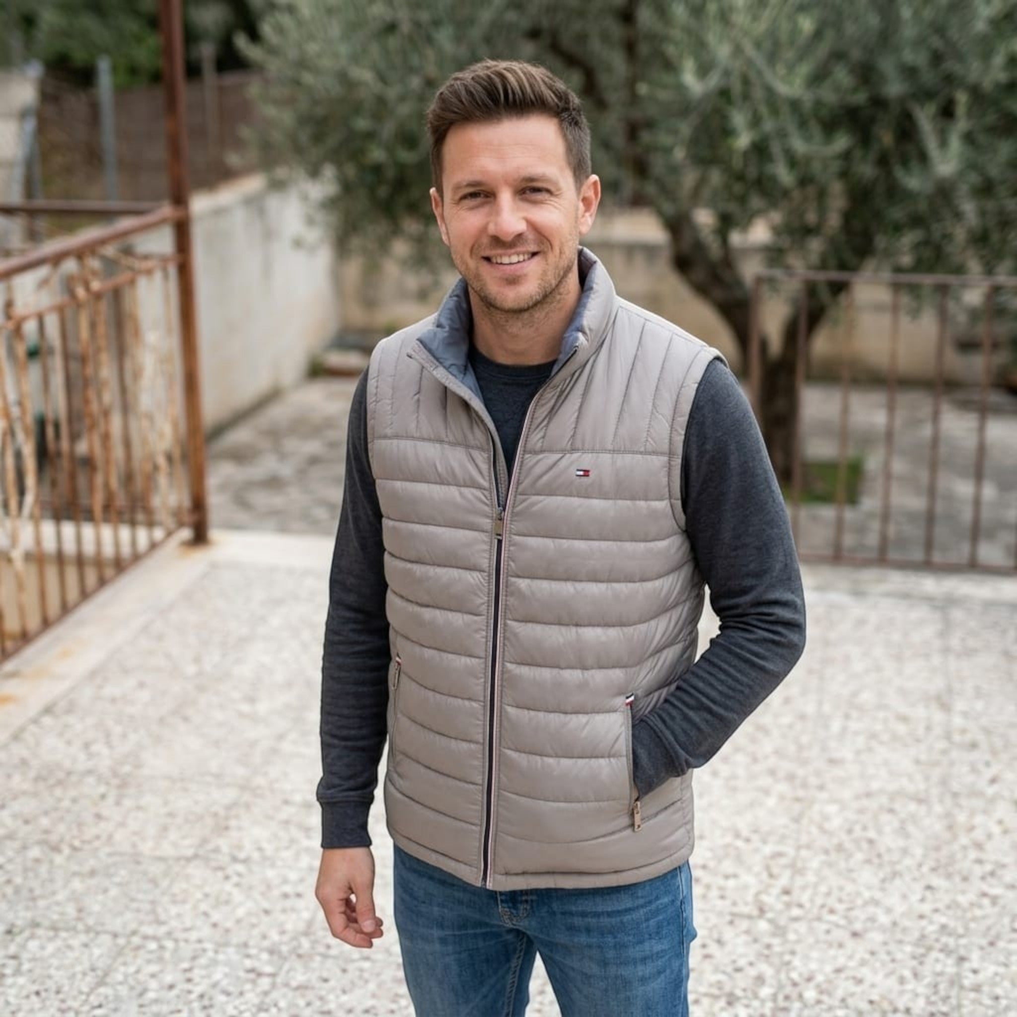 City Center model wearing a light grey Tommy Hilfiger quilted puffer vest over a dark grey long-sleeve shirt