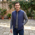 City Center model wearing a navy blue Tommy Hilfiger quilted puffer vest over a grey sweater in an outdoor courtyard