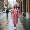City Center Top In Town transparent pink patterned raincoat with hood worn by a woman holding a clear umbrella