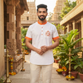 City Center white cotton short kurta with orange trim and Ganesha embroidery worn by a man in a temple setting