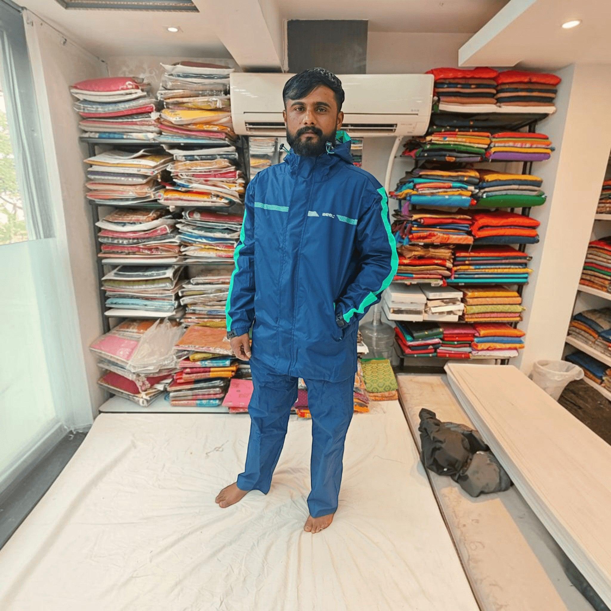 City Center ZEEL premium blue waterproof rainsuit with hood and green accents worn by a man in a retail store
