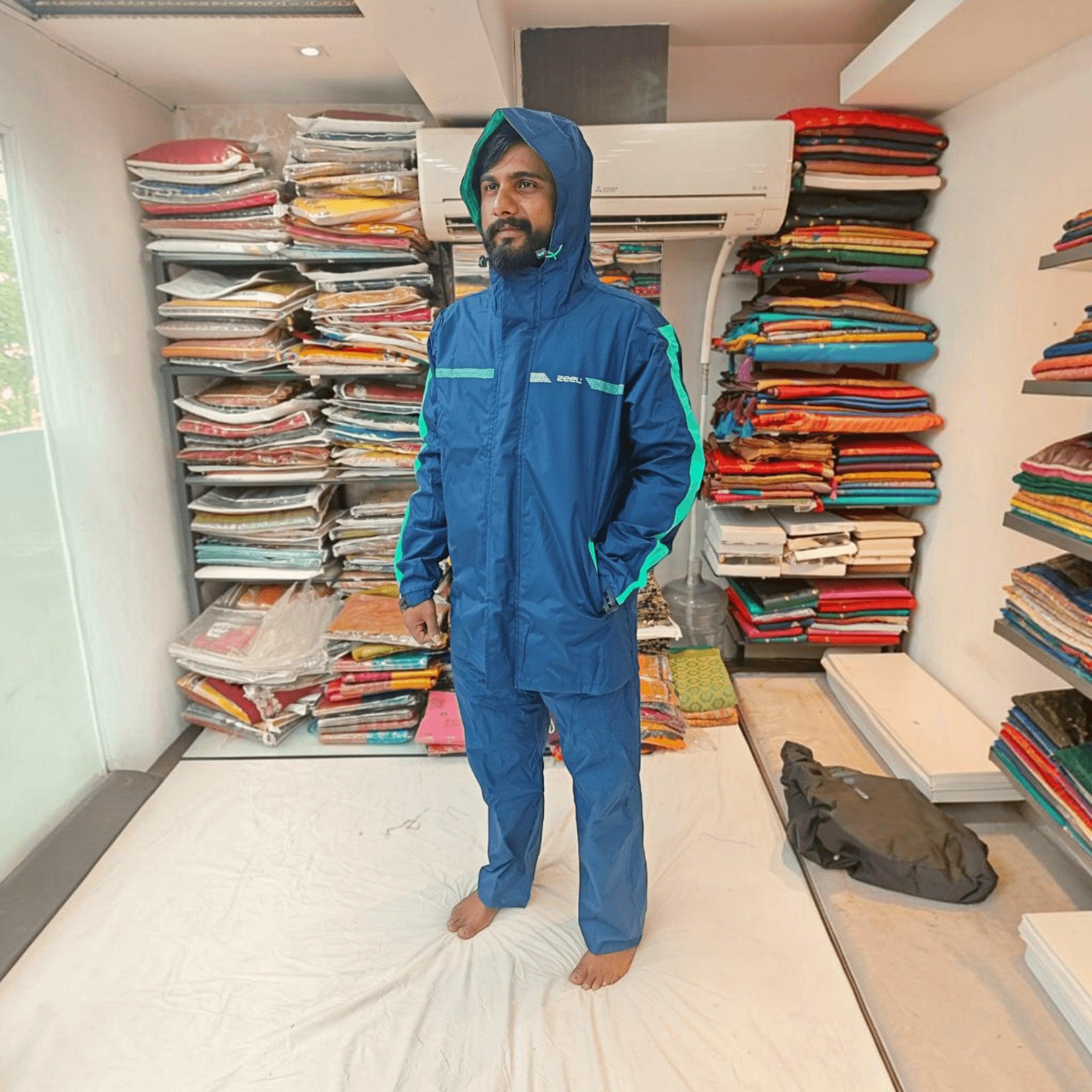 City Center ZEEL premium blue waterproof rainsuit with hood and green accents worn by a man in a retail store