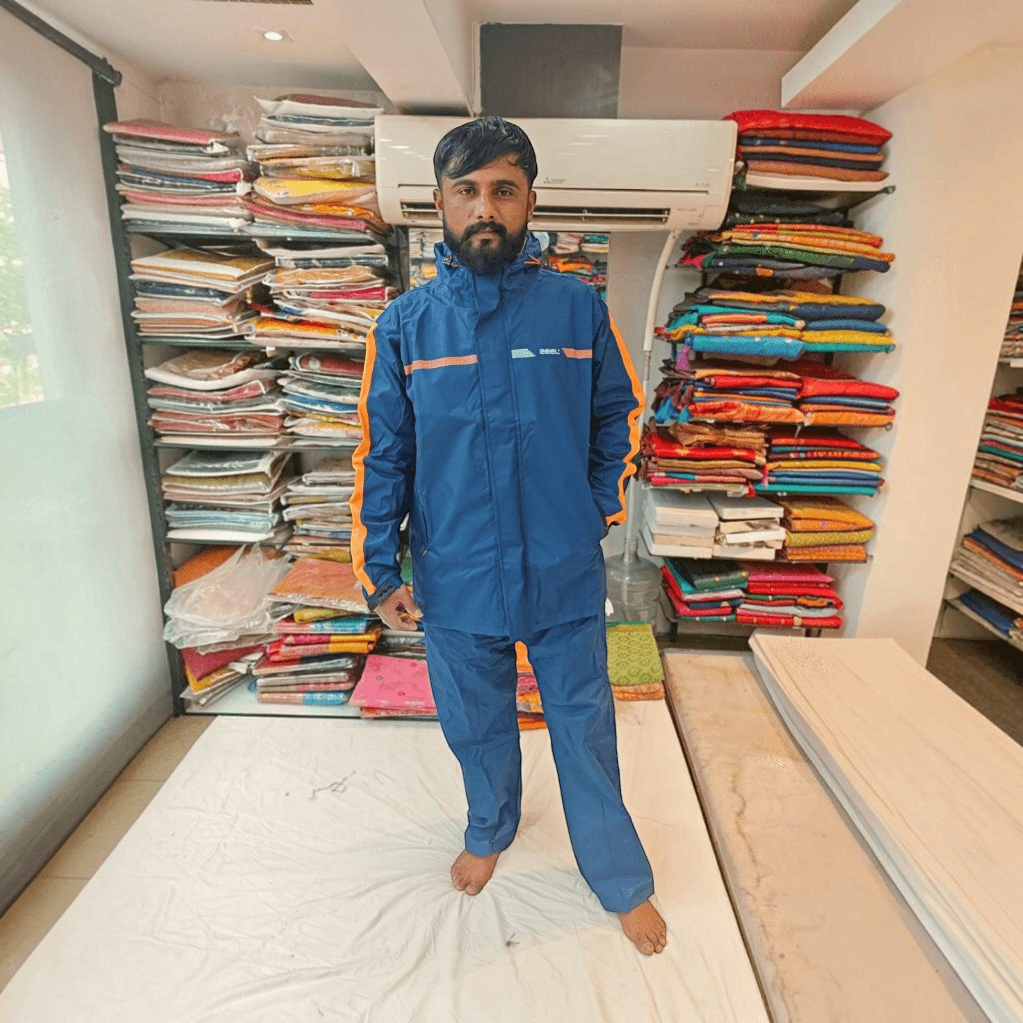 City Center ZEEL premium blue waterproof rainsuit with orange side stripes worn by a man in a retail store setting
