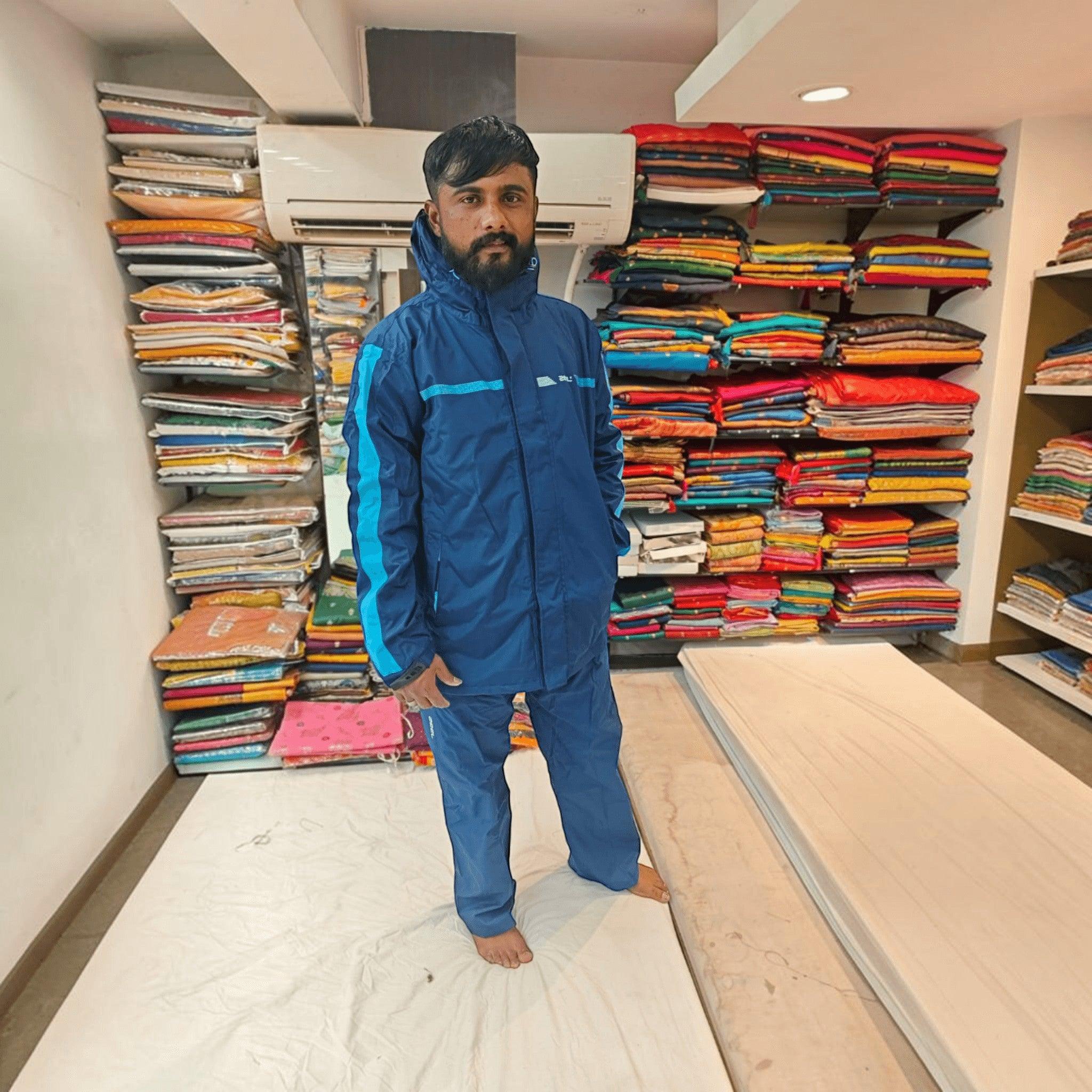 City Center ZEEL premium blue waterproof rainsuit with hood worn by a man in a retail store setting.