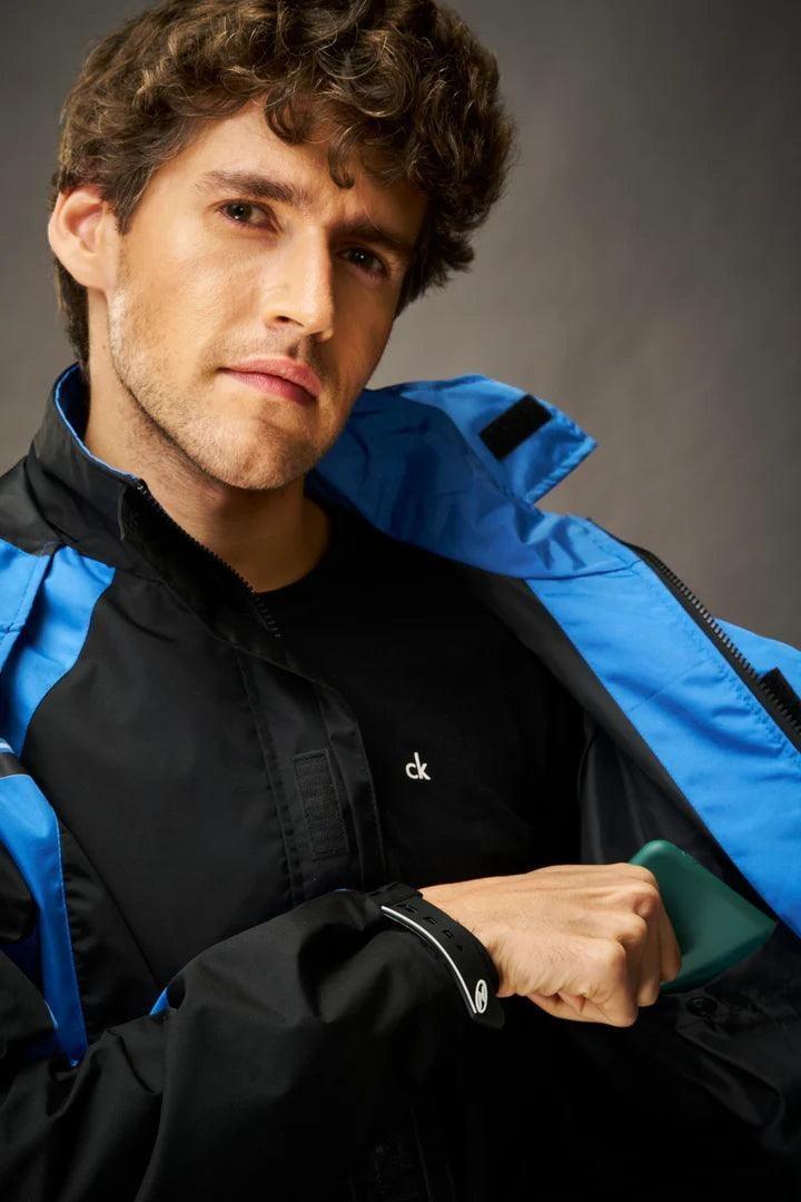 City Center Zeel Go Hike black and blue waterproof rainsuit with storm flap and adjustable cuffs worn by a man